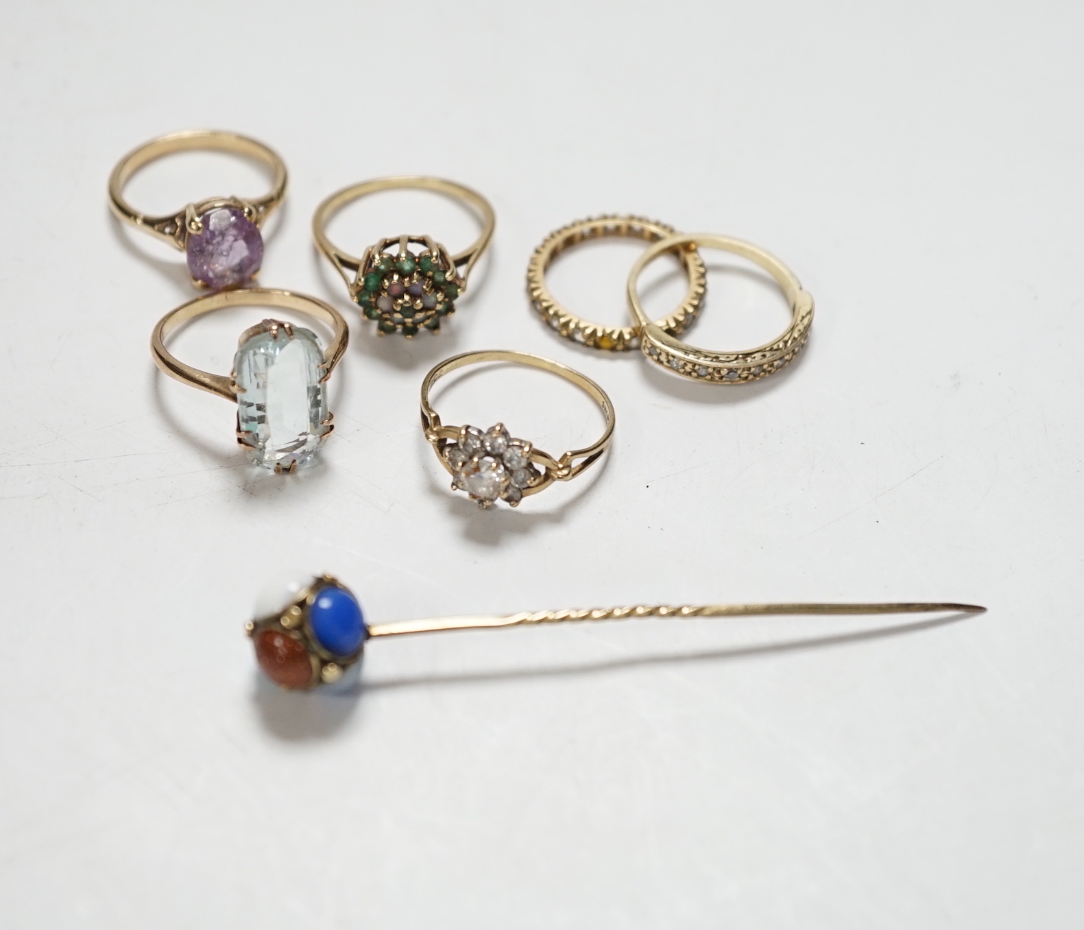 Four assorted modern 9ct and gem set rings including cubic zirconia, two other yellow metal and gem set rings including aquamarine and a yellow metal and multi gem set stick pin, gross weight 15.8 grams.